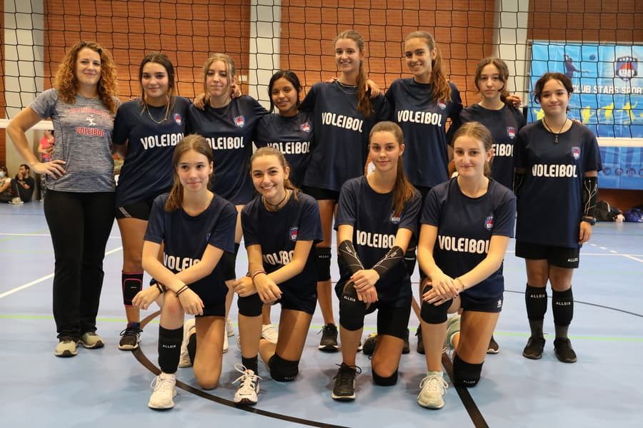 Jugadores del equipo juvenil femenino celebrando la victoria en un partido de voleibol de interior
